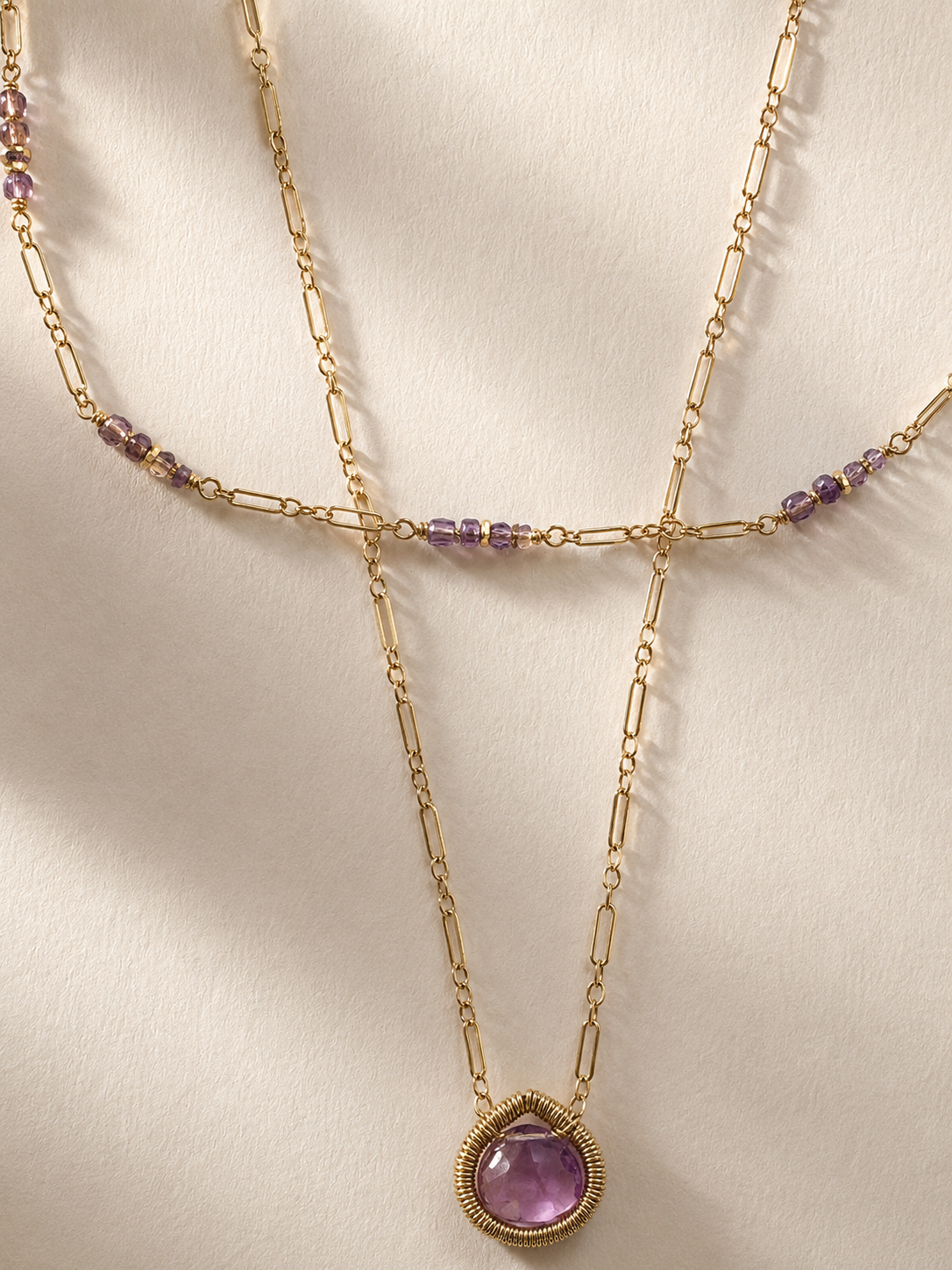 Gold double-strand necklace with purple bead stations and round amethyst pendant