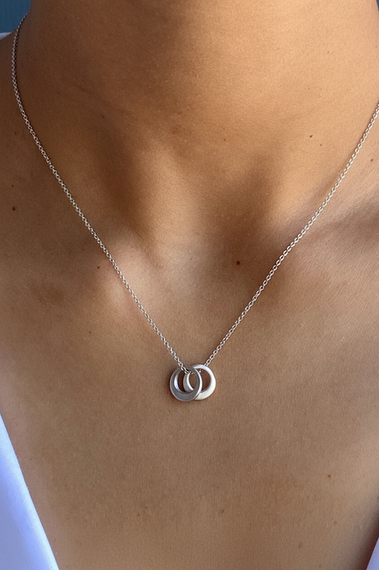 Silver-tone pendant necklace with two linked round rings on the collarbone