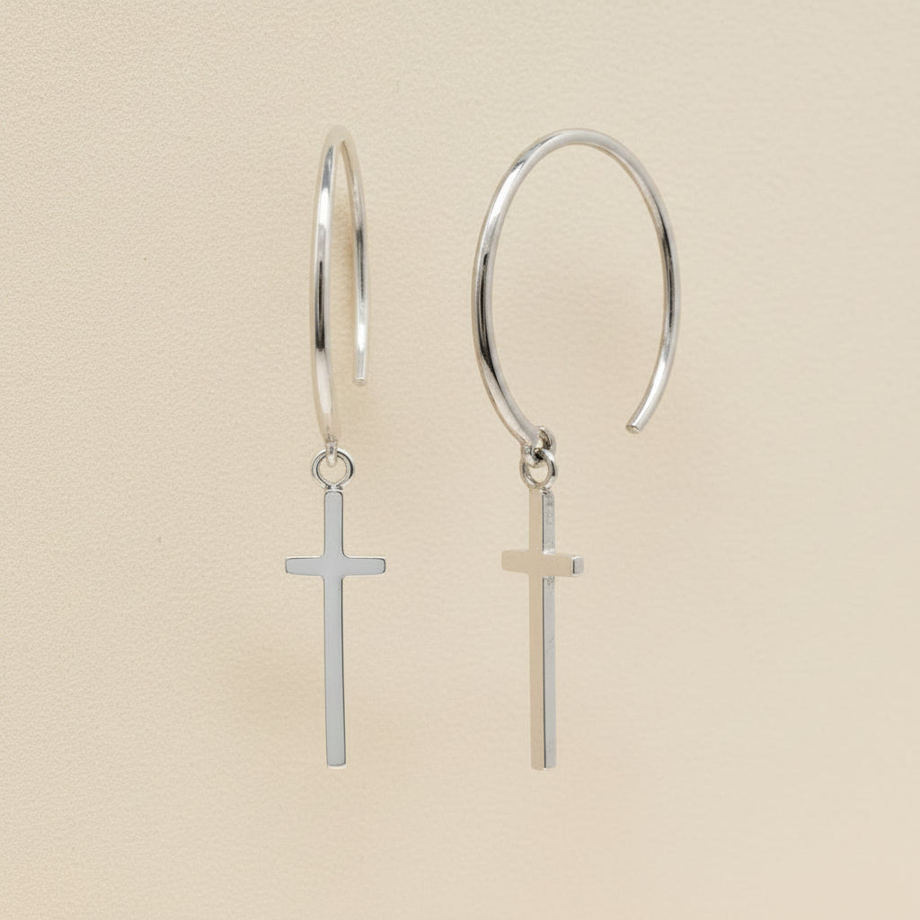 Silver hoop earrings with small cross charms dangling from hinged loops