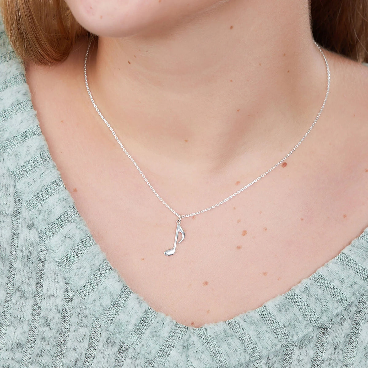 Silver-tone chain necklace with quarter note pendant at collar