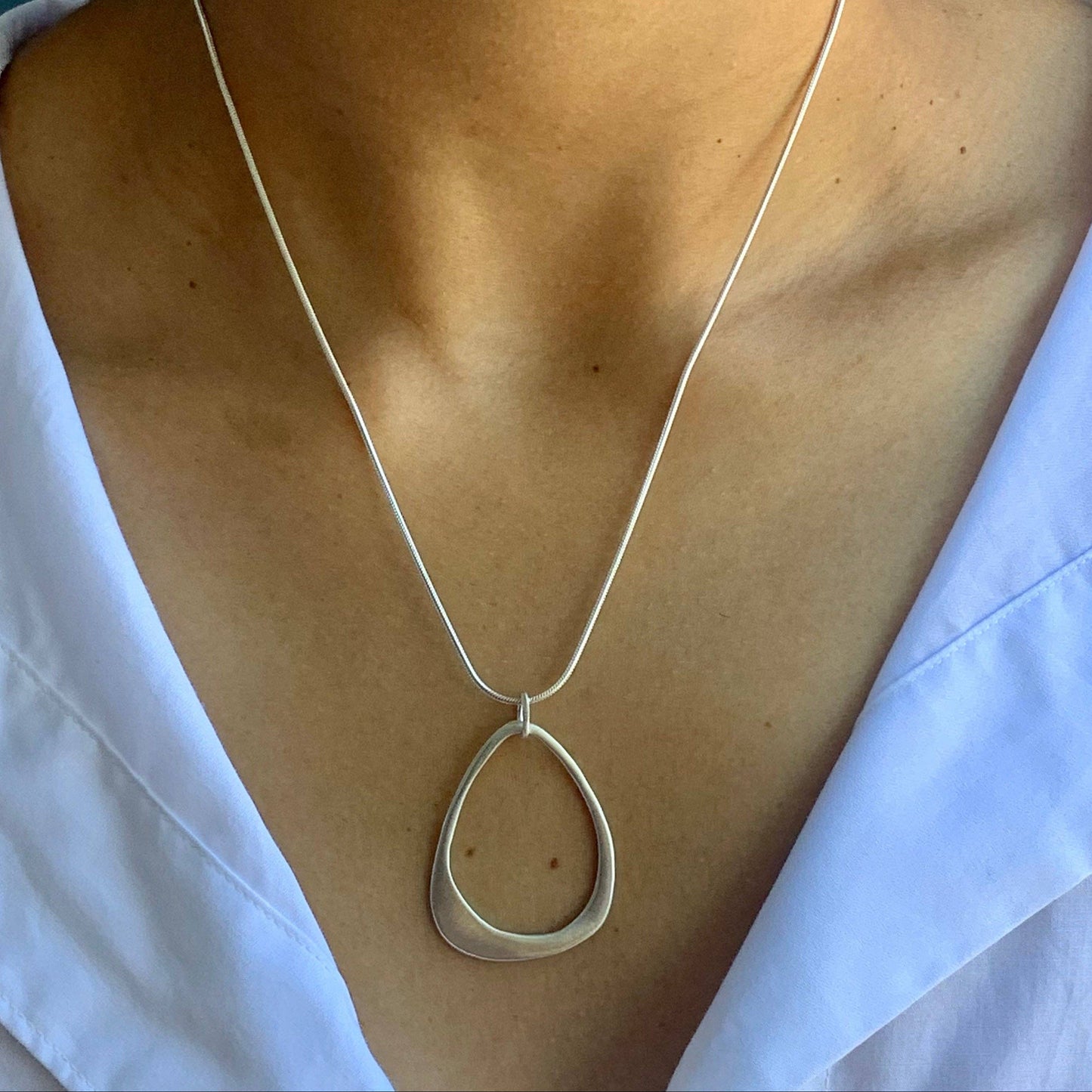 Open teardrop pendant necklace hanging on silver chain