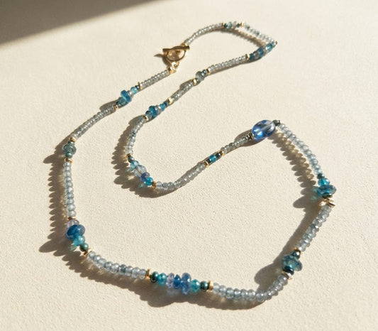 Blue beaded choker necklace with gold bird charm and tiny teal bead accents