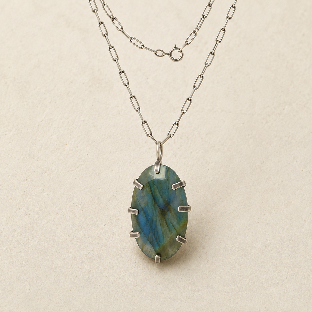 Oval labradorite pendant on silver-tone chain, faceted blue-green stone with metal prongs