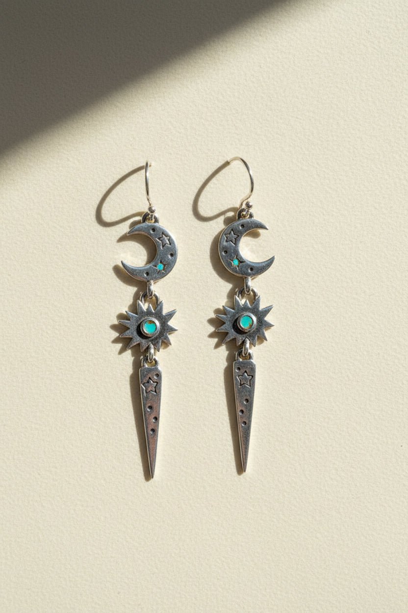 Stardust earrings with dangling crescent moons, blue starburst gems, and long teardrop charms