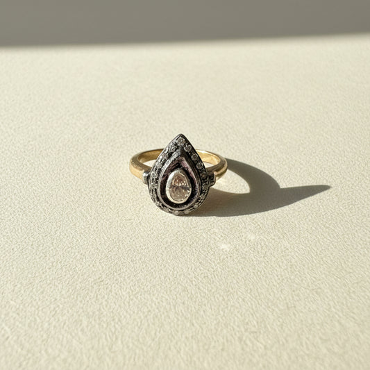 Two-tone teardrop diamond ring with pave halo and round center stone on gold band