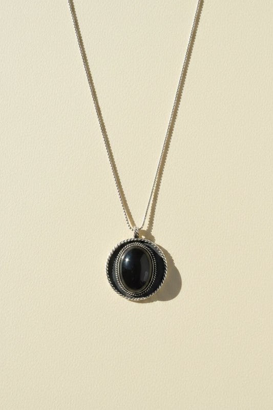 Shield pendant necklace with dark oval cabochon in textured round bezel