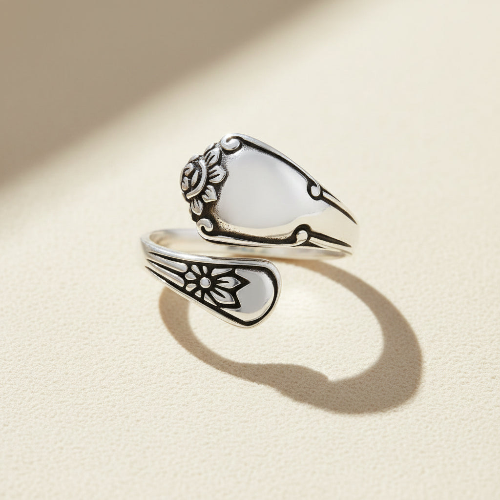 Silver spoon-shaped ring with engraved floral swirls and curved band
