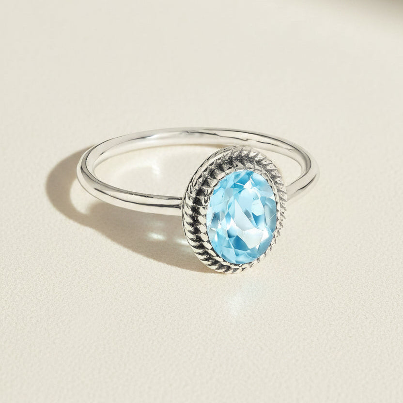 Silver oval gemstone ring with light blue stone set in rope bezel