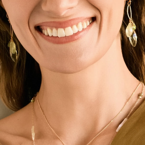 Green gemstone drop earrings on silver hooks, worn close-up