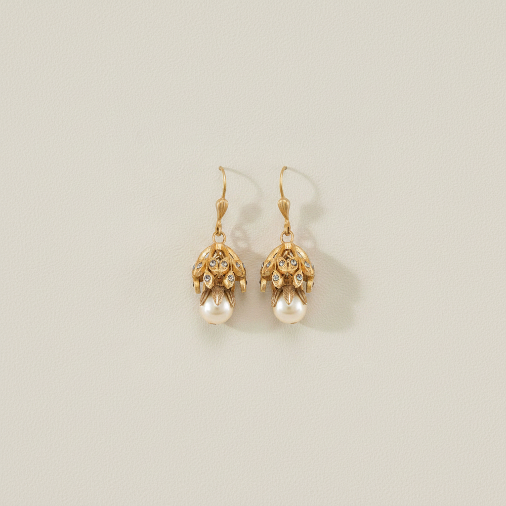Gold-tone drop earrings with filigree caps and hanging faux pearl, side view