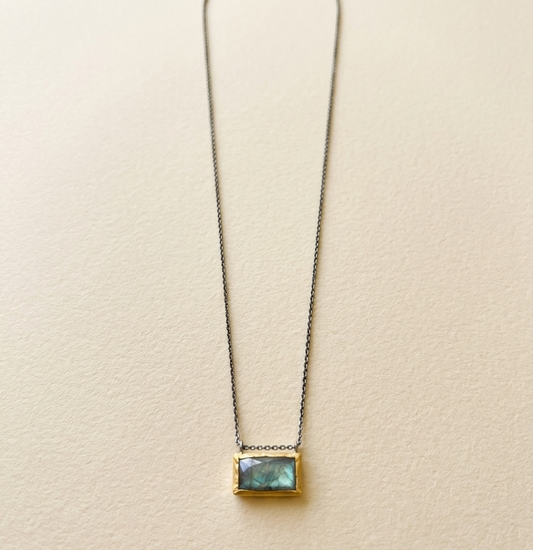 Rectangle pendant necklace with blue-green gem and gold-tone frame on a fine chain