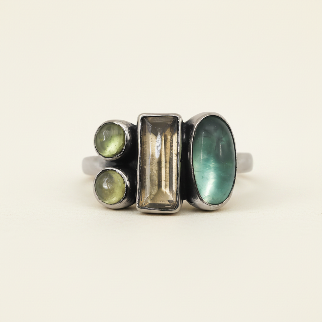 Multi-stone ring with rectangular center and three green-toned stones in dark settings
