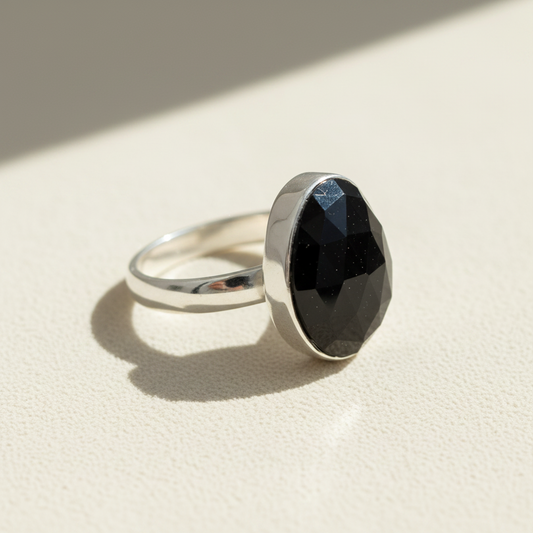 Silver statement ring with black oval faceted stone, angled