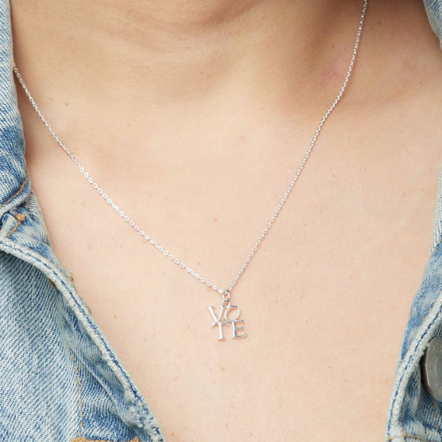 Silver-tone VOTE pendant necklace resting on neckline