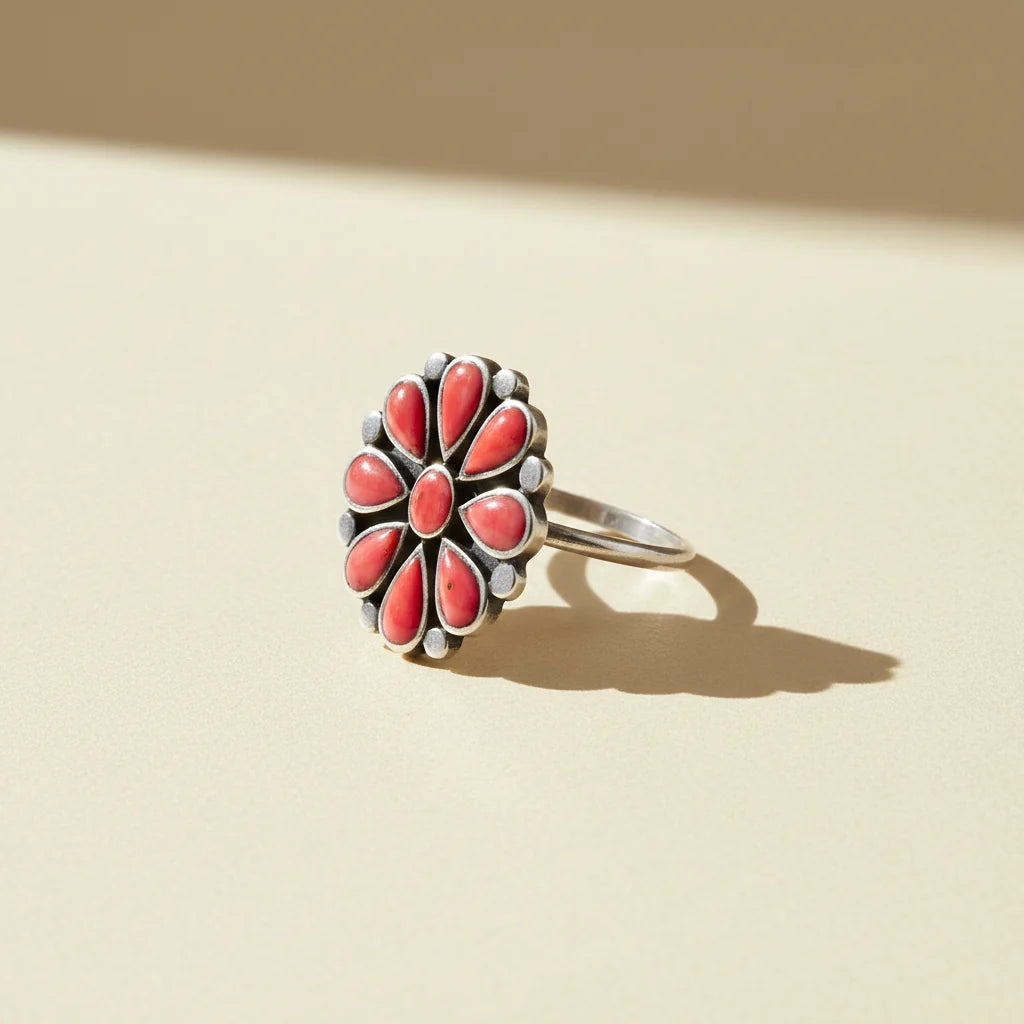 Coral flower ring with silver-tone band and red teardrop stone petals, side view
