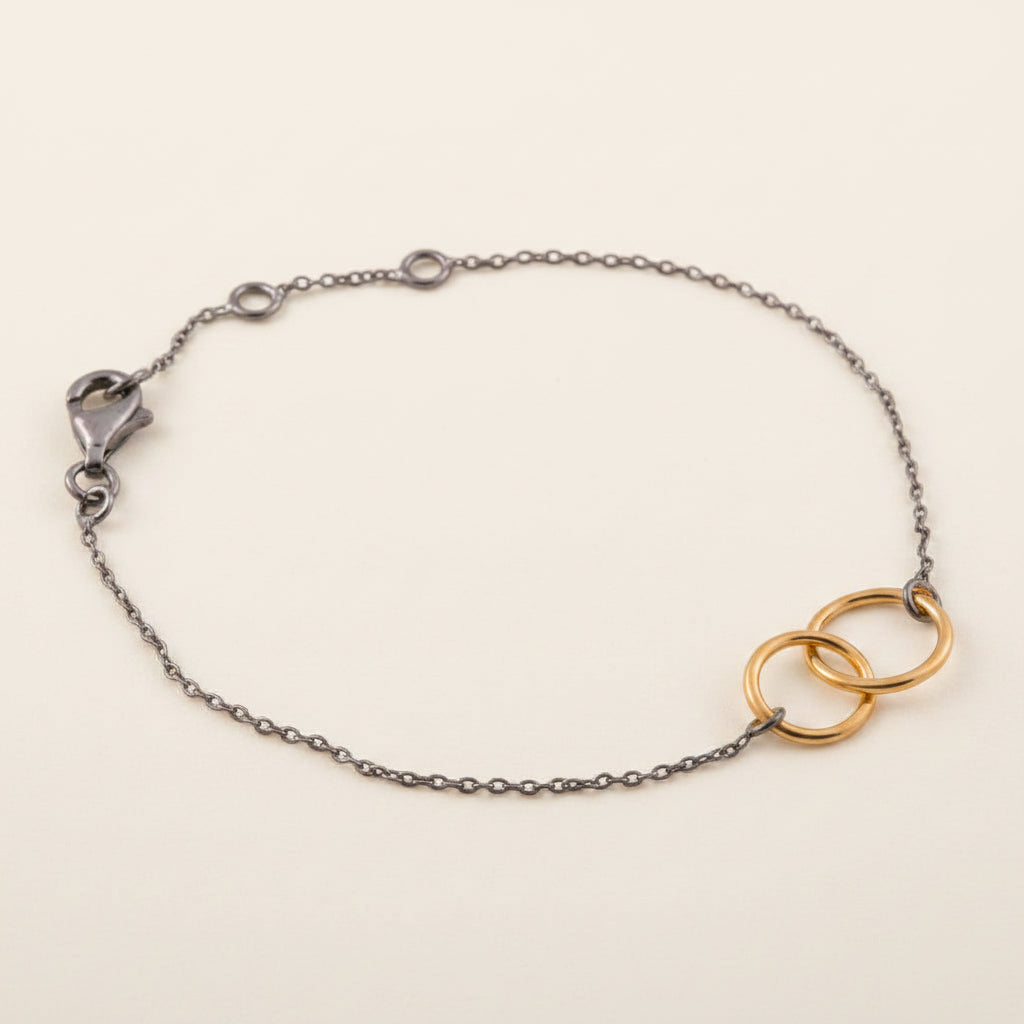 Bracelet with silver chain and gold interlocking rings on a white background
