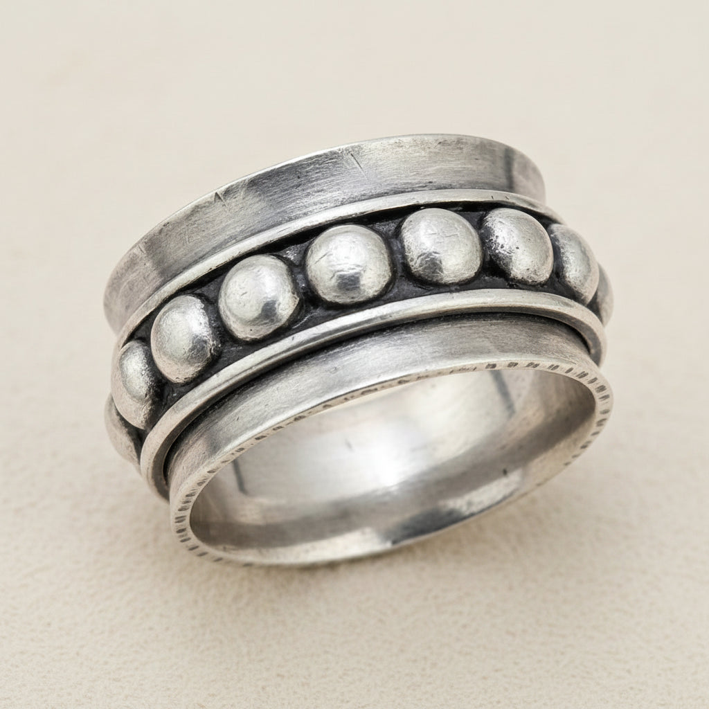 Silver spinner ring with raised round bead details on the outer band