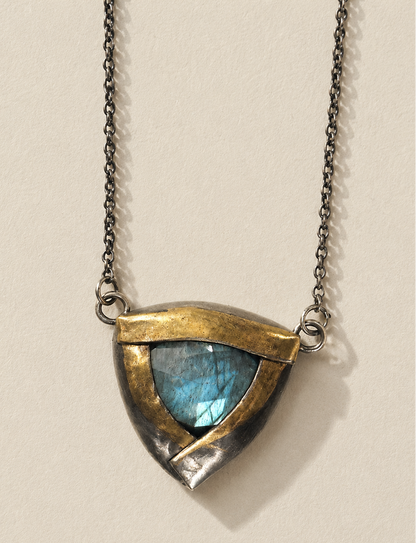Shield-shaped pendant necklace with blue stone, gold-tone frame, chain