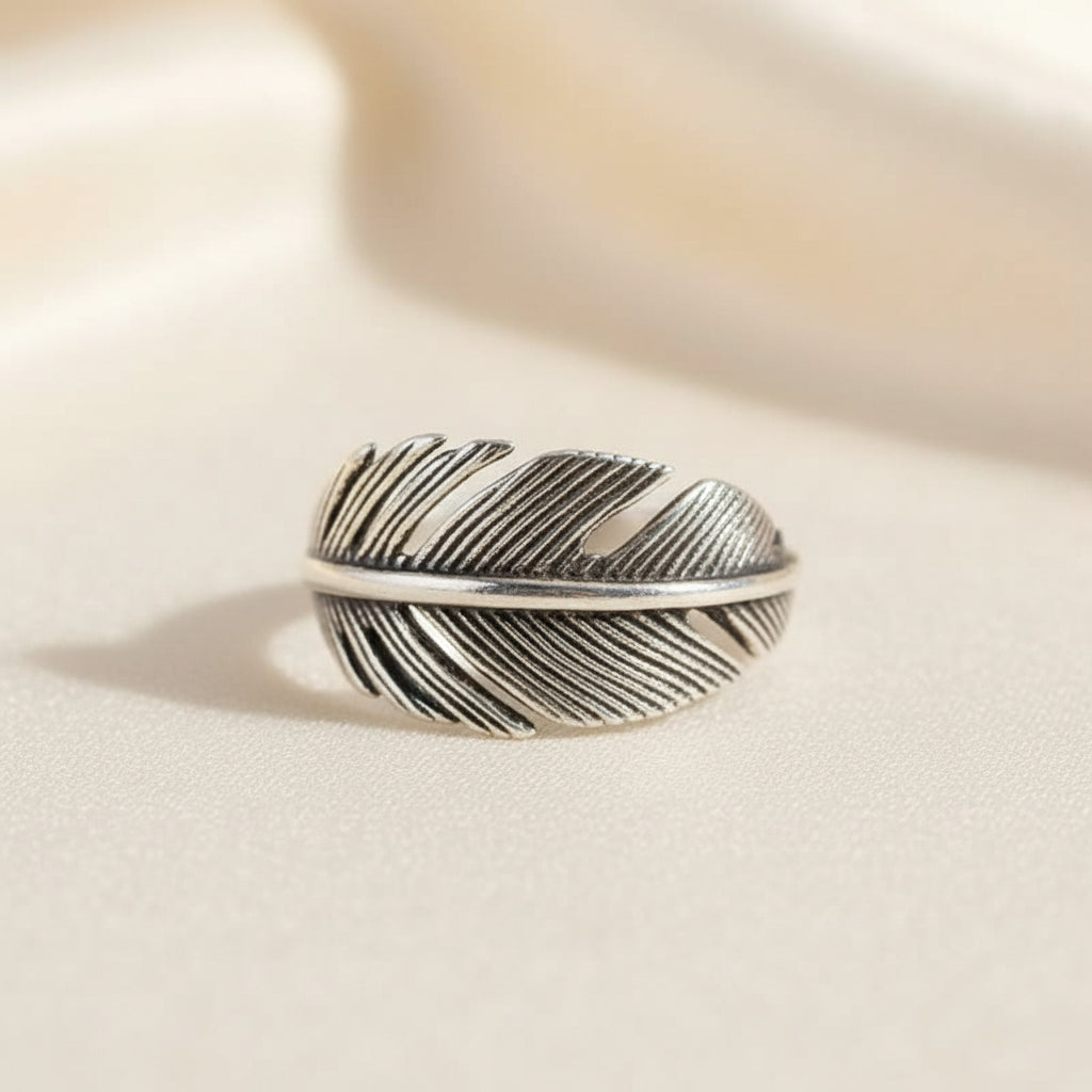Silver feather-shaped ring on a white background