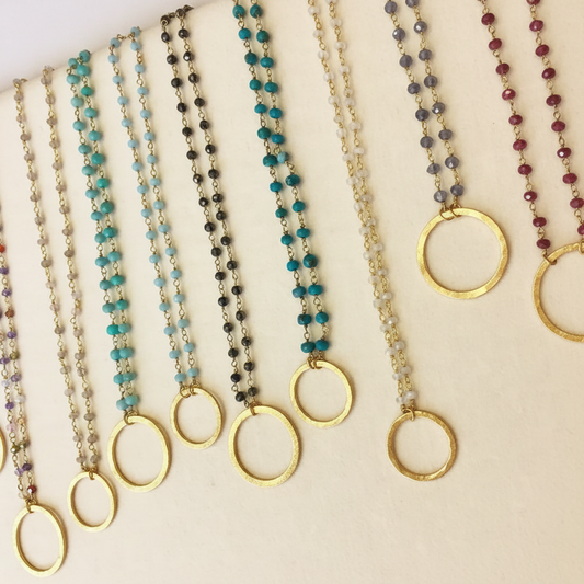 Beaded necklaces with gold ring pendants and faceted beads in turquoise, black, and gold