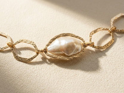 Gold-tone bracelet with hammered oval links and large white pearl center detail