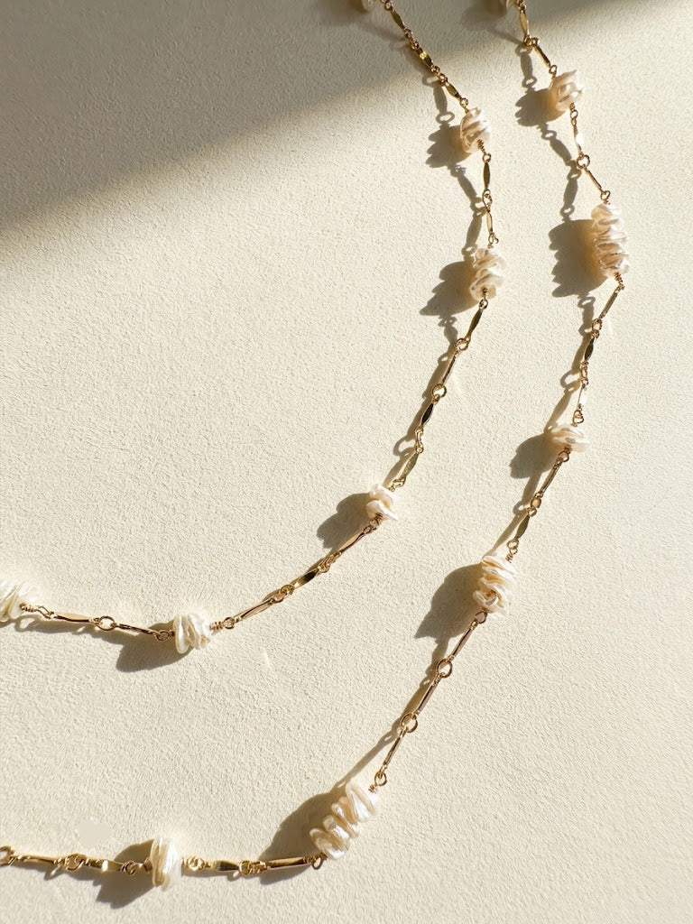 Long gold-tone chain necklace with keshi pearls and leaf-like shell drops