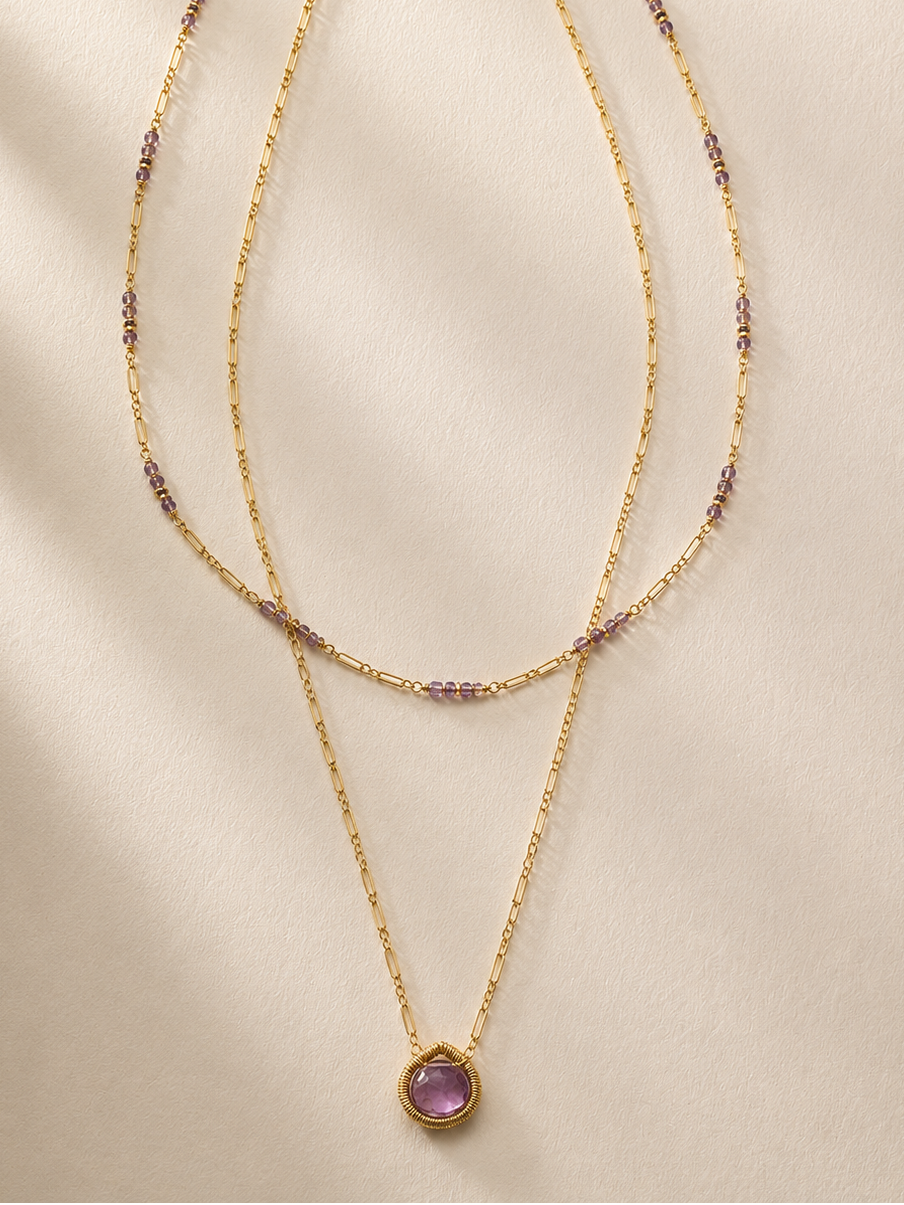 Gold layered necklace with purple bead accents and round purple pendant, long drape