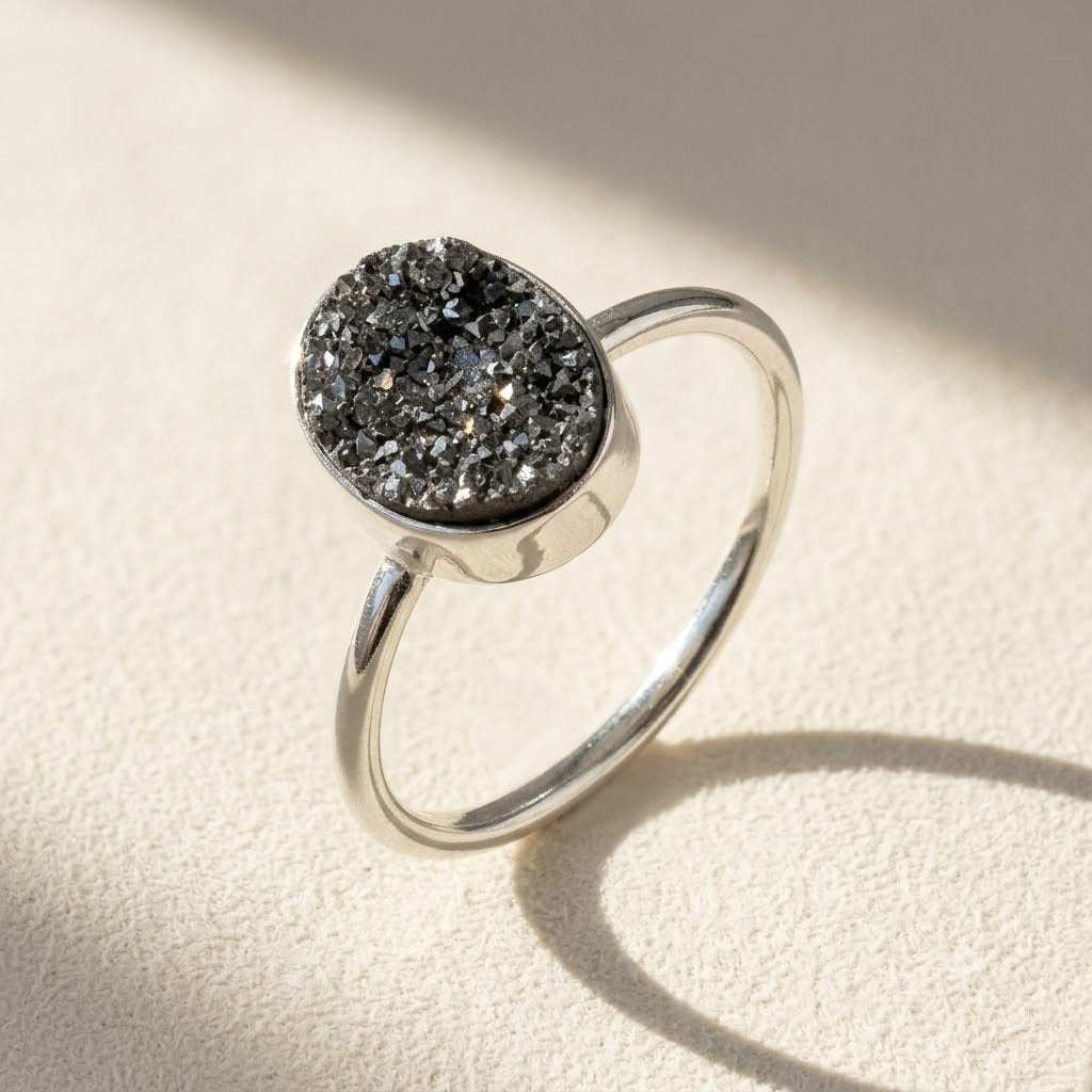 Oval druzy stone ring with dark gray sparkling cluster and polished silver band