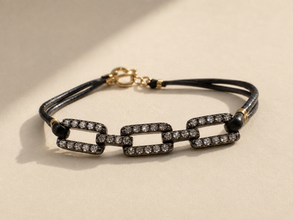 Pave diamond chain link bracelet on black cord with gold clasp and black bead accents