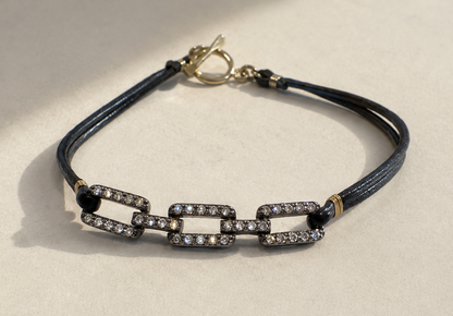 Pave diamond chain link bracelet with dark blue cord, black beads, and small heart clasp