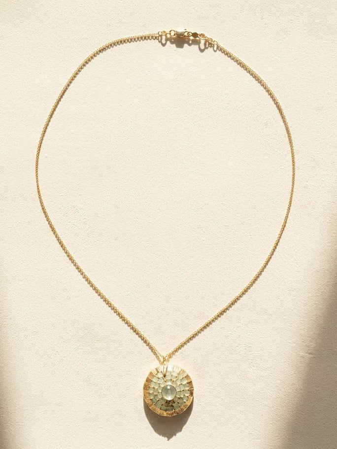 Gold-tone necklace with thin chain and round pendant with faceted crystal center