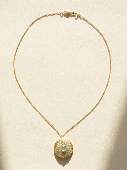 Gold-tone necklace with thin chain and round pendant with faceted crystal center