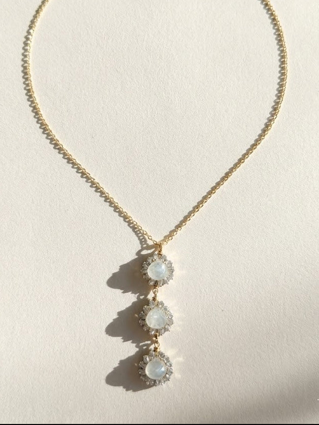 Gold pendant necklace with three dangling round opal-like stones on a thin chain