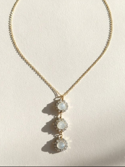 Gold pendant necklace with three dangling round opal-like stones on a thin chain