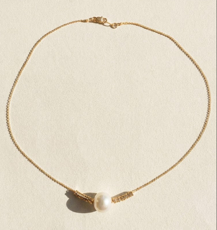 Gold-tone pearl pendant necklace with round white pearl and small ribbon-like charms