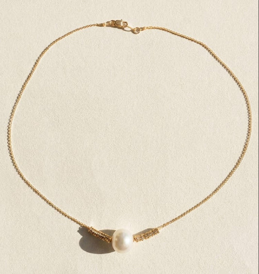Gold-tone pearl pendant necklace with round white pearl and small ribbon-like charms