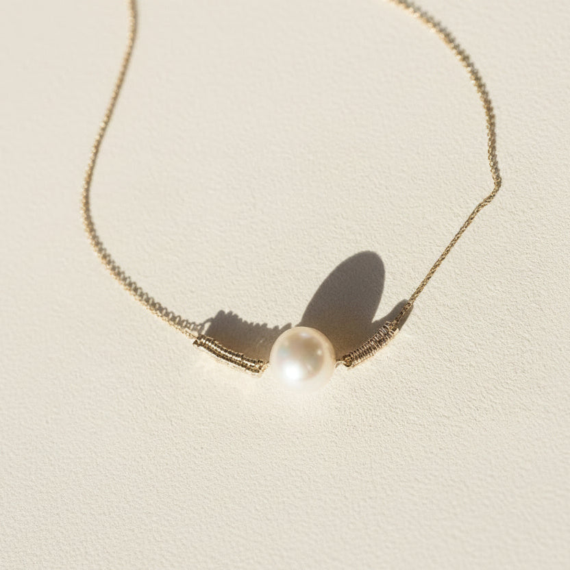 Gold-tone pearl pendant necklace, close view of round white pearl center