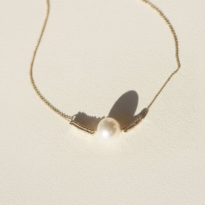 Gold-tone pearl pendant necklace, close view of round white pearl center