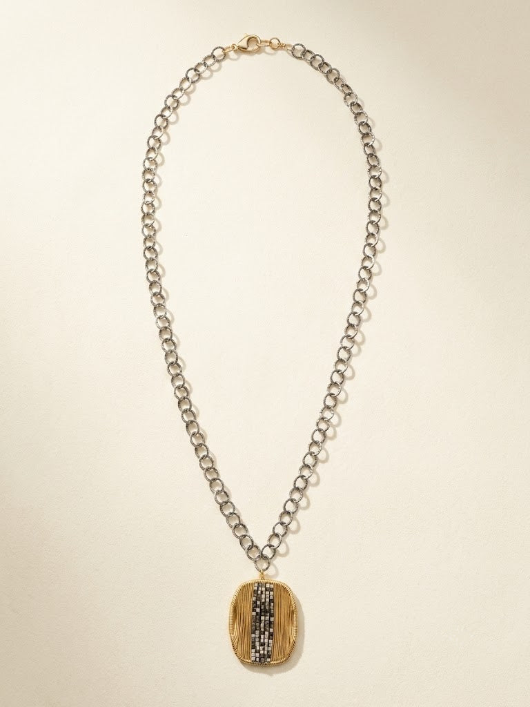 Oval pendant necklace with silver chain and gold-and-dark vertical striped oval medallion