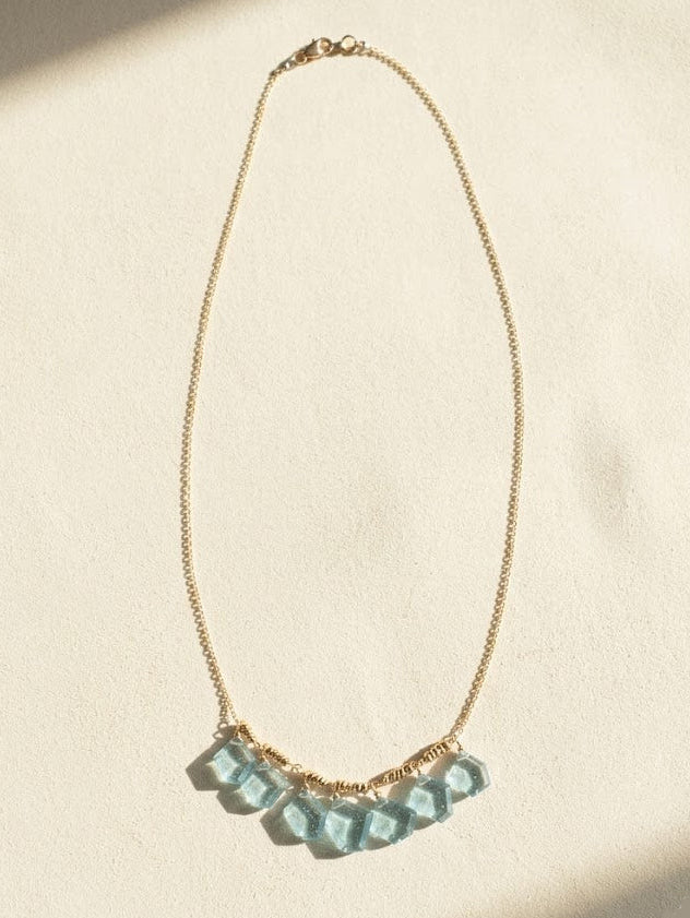 Gold chain necklace with light blue faceted slice beads in a curved row
