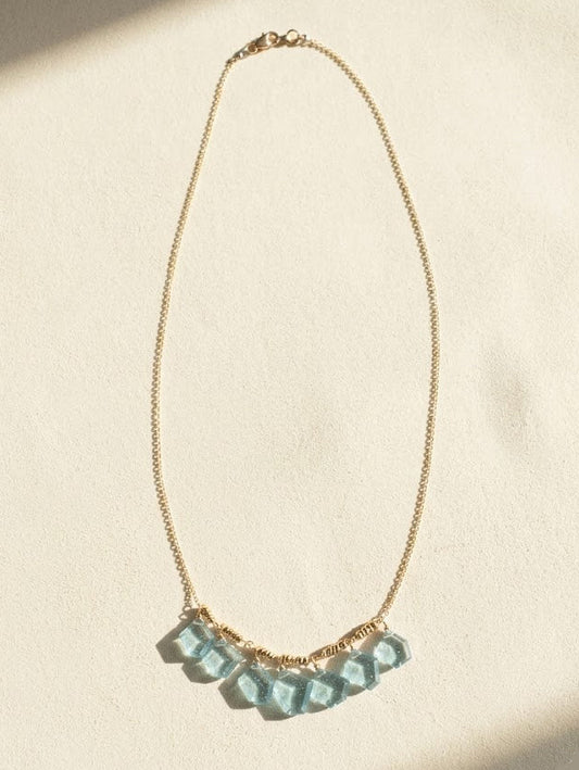 Gold chain necklace with light blue faceted slice beads in a curved row