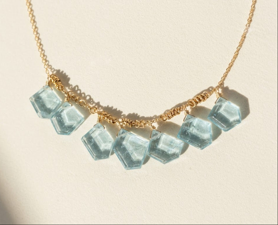 Gold chain necklace with light blue glass slice beads along the front