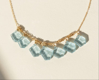 Gold chain necklace with light blue glass slice beads along the front