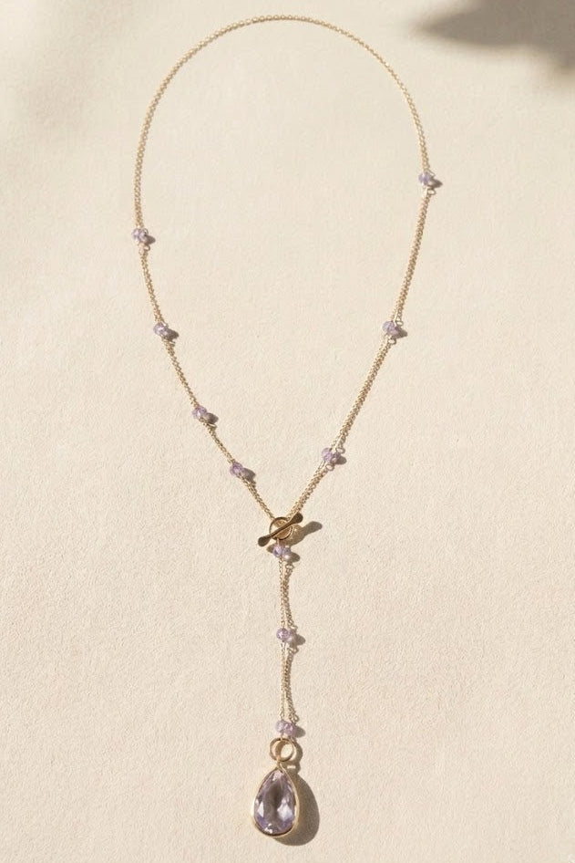 Gold lariat necklace with lilac bead sections and dangling teardrop pendant