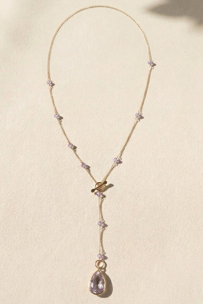 Gold lariat necklace with lilac bead sections and dangling teardrop pendant