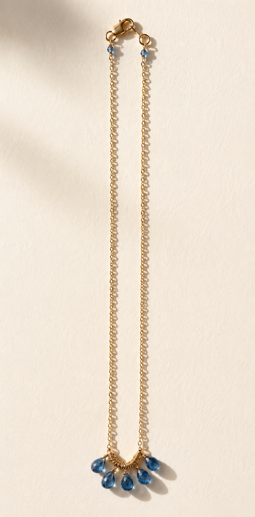 Long gold-tone briolette necklace with blue teardrop cluster at center