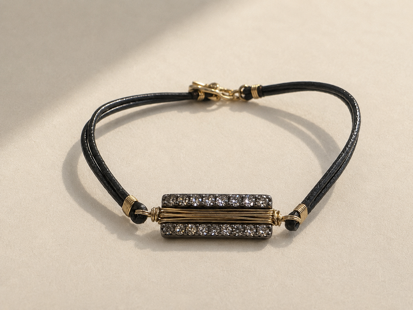 Black cord bracelet with gold bar centerpiece and adjustable sliding clasp