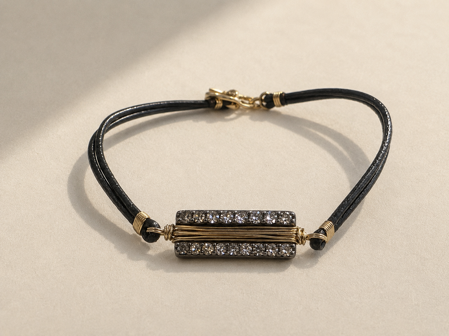 Black cord bracelet with gold bar centerpiece and adjustable sliding clasp