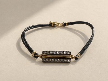 Black cord bracelet with gold bar centerpiece and adjustable sliding clasp