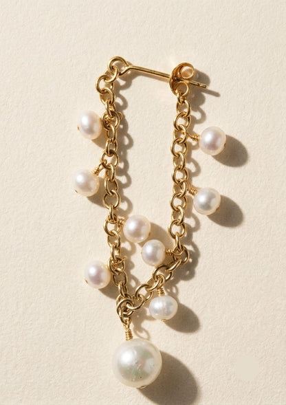 Gold hoop chain earrings with dangling white pearls and one large pearl drop